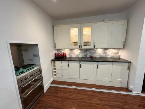 a kitchen with white cabinets and a sink and a stove at 2 bedroom flat Wembley in London