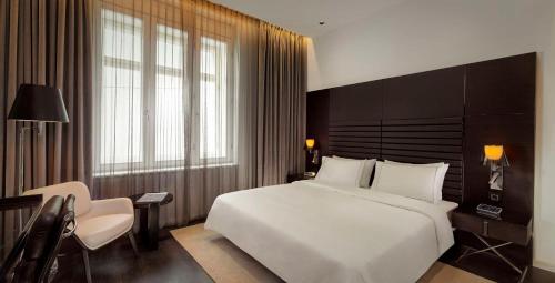 1 dormitorio con 1 cama blanca grande y 1 silla en art'otel Rome Piazza Sallustio, Powered by Radisson Hotels, en Roma