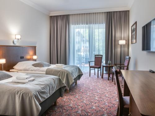 ein Hotelzimmer mit zwei Betten und einem Tisch in der Unterkunft Medica Hotel Krojanty Bory Tucholskie in Chojnice