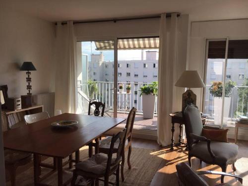 una sala da pranzo con tavolo e sedie e un balcone di Appartement 70m2 terrasse vue jardin 10min Paris centre a Levallois-Perret