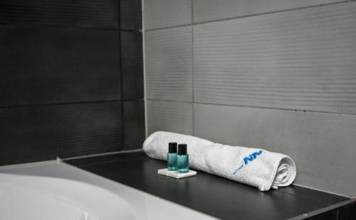 uma casa de banho com uma banheira com uma toalha e um vidro em NN Boutique Hotel**** em Tiszaújváros