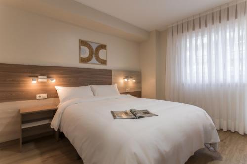sypialnia z dużym białym łóżkiem i oknem w obiekcie Vigo Bay Apartments by Olala Homes w mieście Vigo