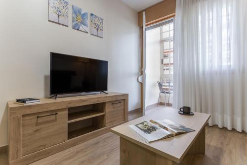 Il comprend un salon doté d'une télévision à écran plat et d'une table basse. dans l'établissement Vigo Bay Apartments by Olala Homes, à Vigo