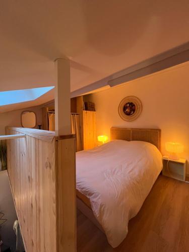 a bedroom with a large bed with white sheets at Petite maison au cœur de la pinède in Lacanau