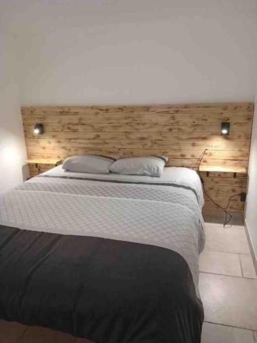 une chambre avec un grand lit avec une tête de lit en bois dans l'établissement Appartement Rez de maison proche mer, à La Londe-les-Maures
