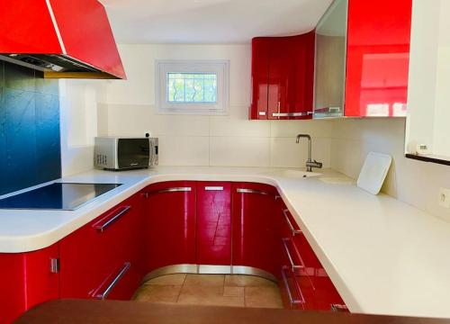 une cuisine avec des armoires rouges et un micro-ondes dans l'établissement Appartement Rez de maison proche mer, à La Londe-les-Maures