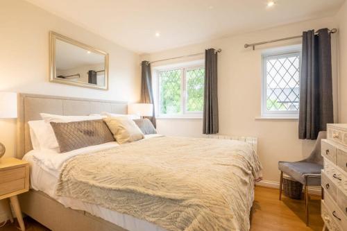 een slaapkamer met een bed, een spiegel en ramen bij Delightful CENTRAL Duplex - 2 Mins To Station in Cambridge