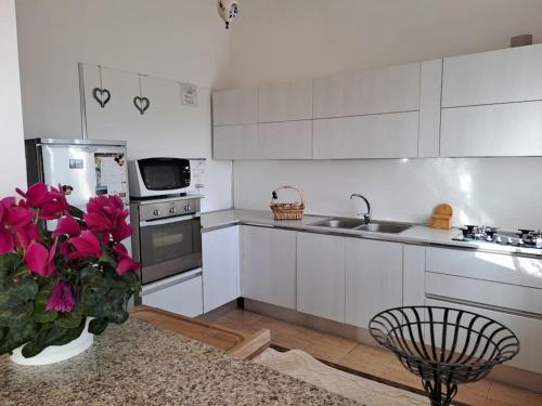 eine Küche mit weißen Schränken und einer Vase mit rosa Blumen in der Unterkunft Nice Apartment in Margine Rosso in Quartu SantʼElena