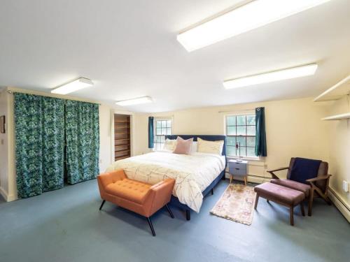 a bedroom with a large bed and a chair at Berkshire Vacation Rentals: Renovated Five Bedrooms In Historic Williamstown in Williamstown