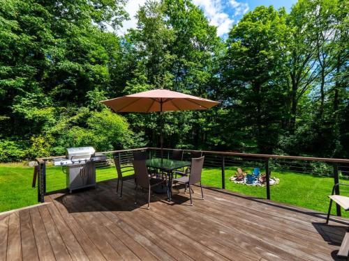 a wooden deck with a table and an umbrella at Berkshire Vacation Rentals: High End Berkshires Getaway in East Hillsdale