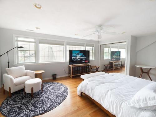 a bedroom with a bed and a tv and a chair at Swampscott Retreat Four Bedrooms Come Unwind in Swampscott