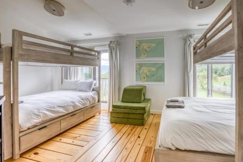 a bedroom with two beds and a green chair at Berkshire Vacation Rentals: The Brookman: Renovated 6000 SF Estate On 40 Acres in Williamstown