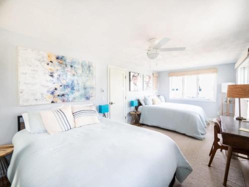 a white bedroom with two beds and a ceiling fan at Tranquil Views On Planting Island Cove in Marion