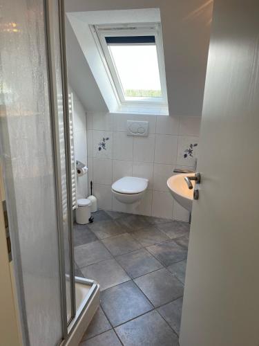 a bathroom with a toilet and a sink and a window at Deichbrise in Greetsiel