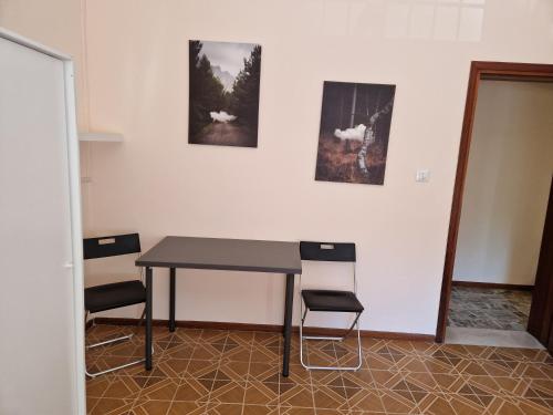 einen Tisch und Stühle in einem Zimmer mit Bildern an der Wand in der Unterkunft Room via Monte 14 in Reggio nell'Emilia