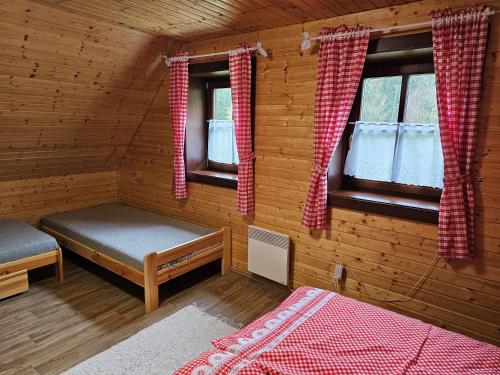 a bedroom of a log cabin with a bed and two windows at Chata na Lazoch so saunou - Raj v prírode in Lazy pod Makytou