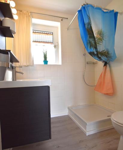 a bathroom with a toilet and a blue shower curtain at Bungalow "Ostseehus" in Grömitz