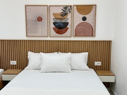 a bedroom with a white bed with three pictures on the wall at Potami Seashell in Himare