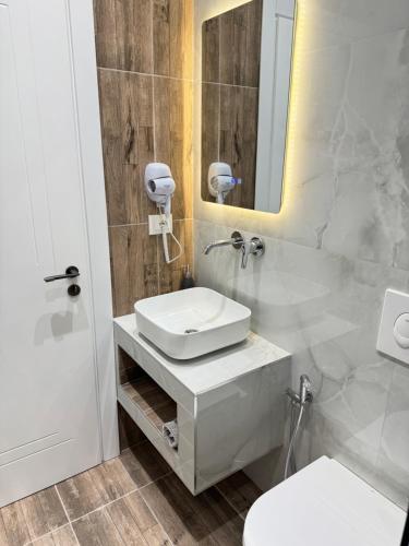 a white bathroom with a sink and a mirror at Potami Seashell in Himare