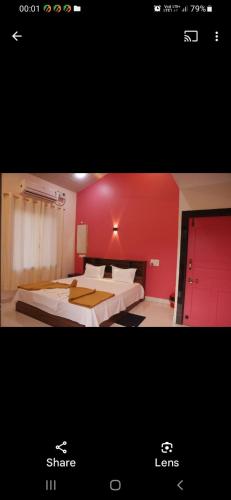 a bedroom with two beds and a red wall at CLASSIC ANAND Bungalow-Blossom Suite, Tarkarli Road, Malvan in Malvan
