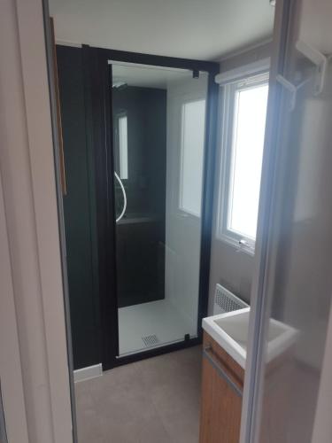 une salle de bain avec un miroir et un lavabo dans l'établissement Mobil-home bord de mer, à Colleville-sur-Mer