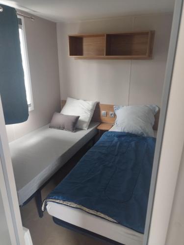 une petite chambre avec deux lits et une fenêtre dans l'établissement Mobil-home bord de mer, à Colleville-sur-Mer