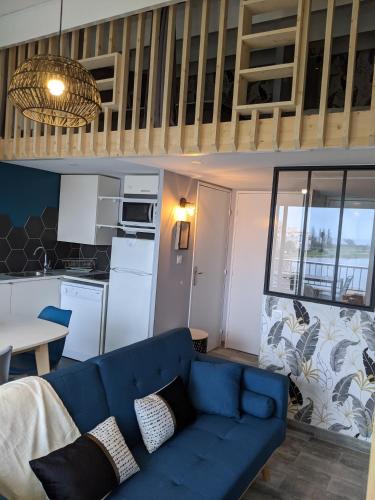 un salon avec un canapé bleu et une cuisine dans l'établissement Duplex Cap d'Agde vue mer avec piscine, au Cap d'Agde