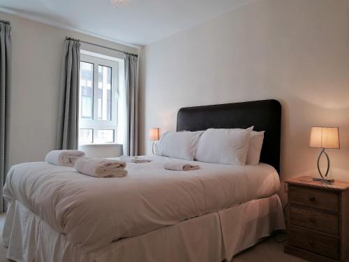 a white bedroom with a large bed with towels on it at Still Life Tower Hill Executive in London