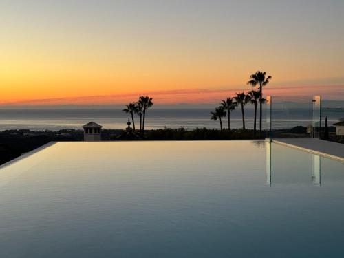 een groot zwembad met een zonsondergang op de achtergrond bij Exclusive VILLA IMAGINE MARBELLA breathtaking panoramic sea views heated infinity pool in Benahavís