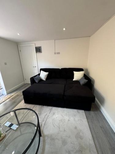 a black couch in a living room with a glass table at Exclusive Lakeside Apartment in Grays Thurrock