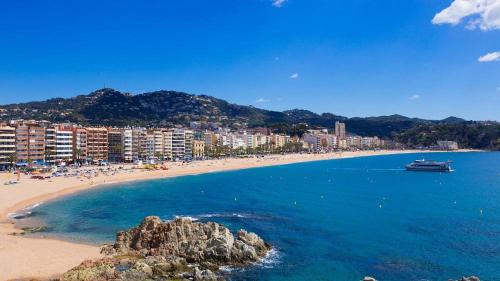 - une plage avec des personnes et un bateau dans l'eau dans l'établissement Apartament Mar Beach Lloret, à Lloret de Mar