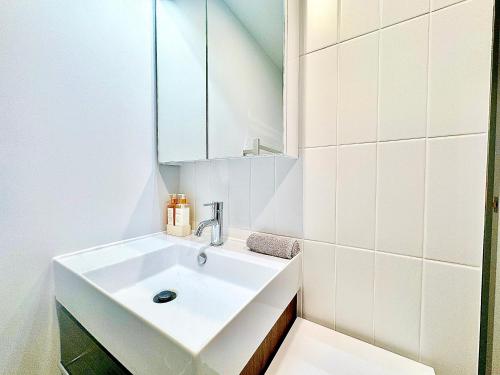 a white bathroom with a sink and a mirror at 2023 Stylish Central Apt+ Free Parking in Wellington
