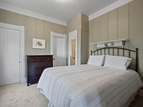 ein Schlafzimmer mit einem großen Bett und einer Holzkommode in der Unterkunft The Zinnia Victorian Charm with Mountain Views in Leadville