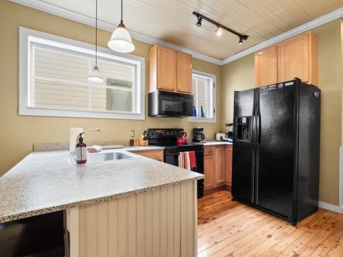 a kitchen with a black refrigerator and wooden cabinets at The Zinnia Victorian Charm with Mountain Views in Leadville
