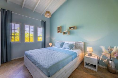 a blue bedroom with a bed and two windows at MasBango Luxury Penthouse at Jan Thiel in Jan Thiel
