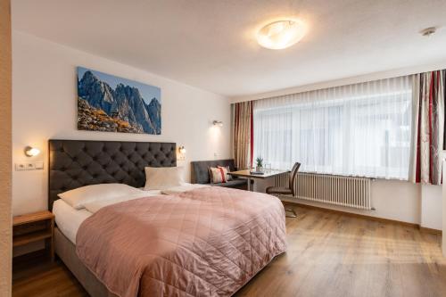 Schlafzimmer mit einem Bett, einem Schreibtisch und einem Fenster in der Unterkunft Appartements Herold in Söll