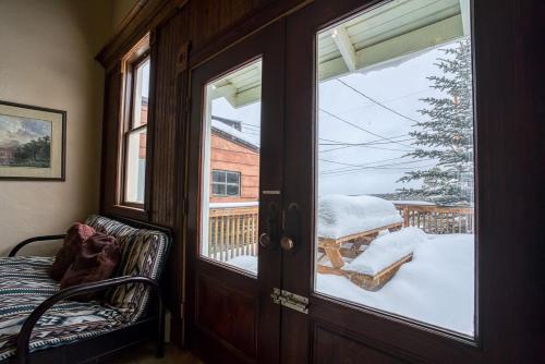 a room with a door open to a balcony with snow at Rosemont in Leadville