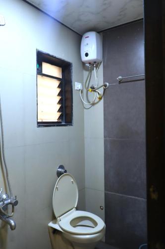 a small bathroom with a toilet and a window at Hotel Midtown Inn in Trimbak