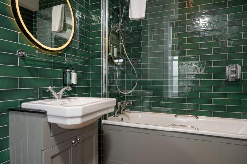 Himley House by Chef & Brewer Collection في Himley: حمام ذو بلاط أخضر مع حوض استحمام ومغسلة
