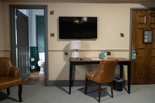 a hotel room with a desk and a television on the wall at Himley House by Chef & Brewer Collection in Himley