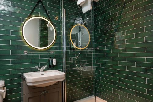 a green tiled bathroom with a sink and two mirrors at Himley House by Chef & Brewer Collection in Himley