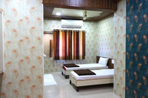 a bedroom with two beds and a curtain at Hotel Midtown Inn in Trimbak