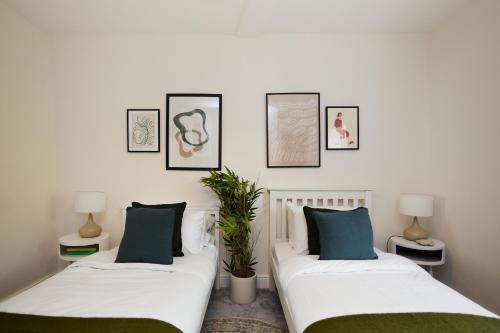two beds in a room with pictures on the wall at The Old Hatfield Haven - Spacious 6BDR House with Garden in Hatfield