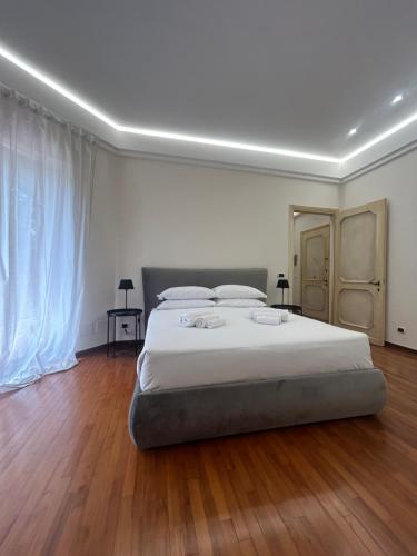 una camera da letto con letto, lenzuola bianche e pavimenti in legno di Lux apartment San Paolo a Roma