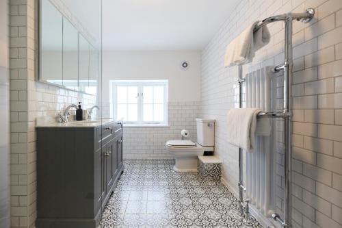 een badkamer met een toilet, een wastafel en een spiegel bij The Old Hatfield Haven - Spacious 6BDR House with Garden in Hatfield