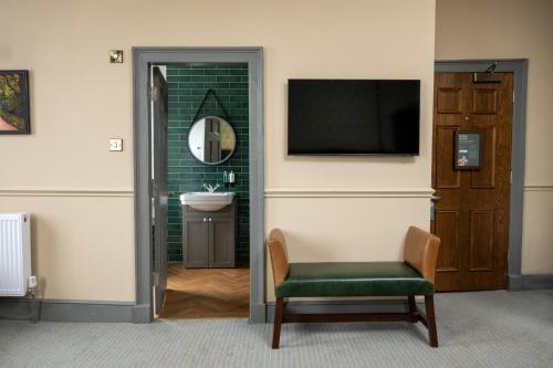 a bathroom with a television and a chair and a sink at Himley House by Chef & Brewer Collection in Himley