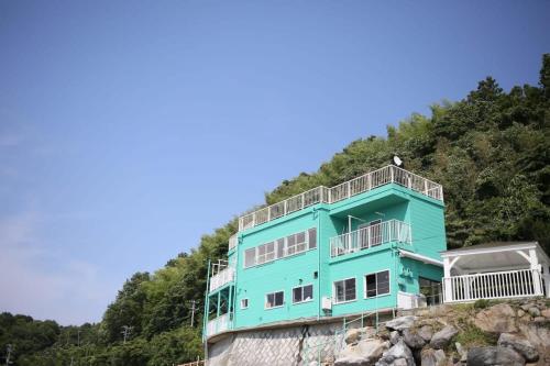 a blue house on the side of a hill at bLOCAL KAI House - with Ocean view good for 8 PPL Free WiFi in Komatsu