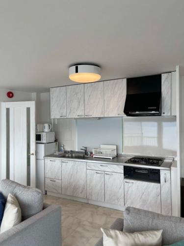 a kitchen with white cabinets and a stove top oven at bLOCAL KAI House - with Ocean view good for 8 PPL Free WiFi in Komatsu