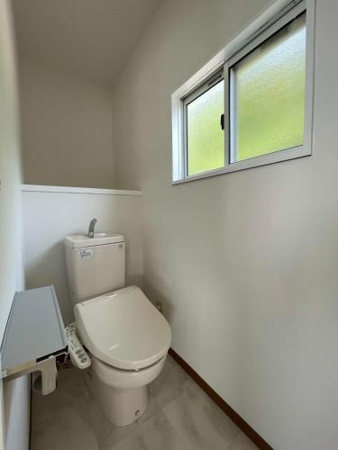 a white bathroom with a toilet and a window at bLOCAL KAI House - with Ocean view good for 8 PPL Free WiFi in Komatsu