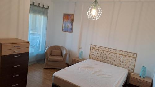 een slaapkamer met een bed, een stoel en een dressoir bij Apartamento Pinseque in Pinseque